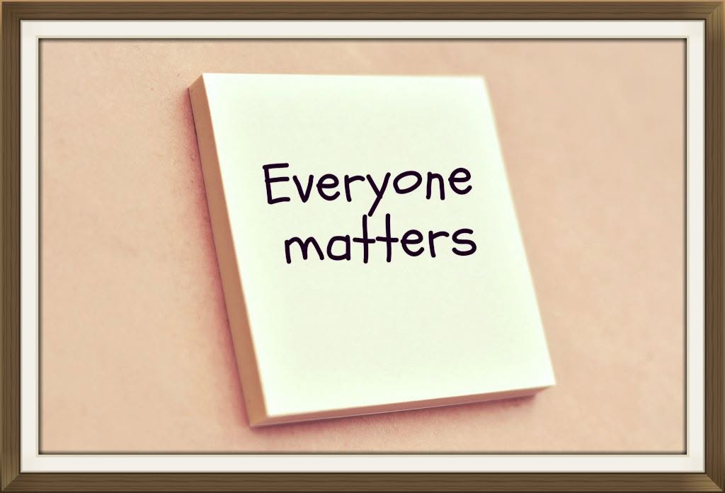 Offenes Notizbuch mit handschriftlichem Text „Everyone matters“ auf hellem Papier, gerahmt auf beigem Hintergrund.